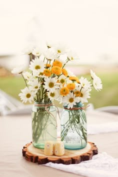 two mason jars filled with white and yellow flowers