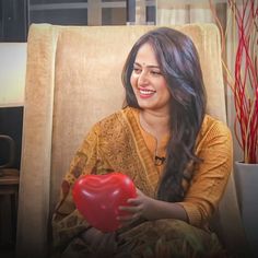 a woman sitting in a chair holding a red heart