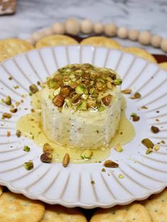 a white plate topped with a cake covered in toppings next to some crackers