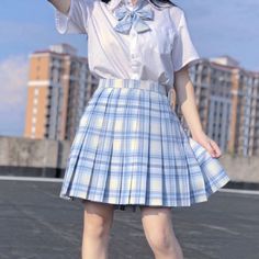 a girl in a blue and white plaid skirt is holding her hand up to the sky