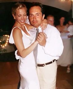 a man and woman dance together on the dance floor in front of people dressed in white