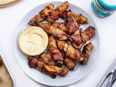 a white plate topped with chicken wings covered in ranch dressing next to a bottle of dip