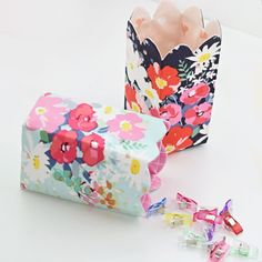 two flowered boxes with candy in them sitting on a table next to each other