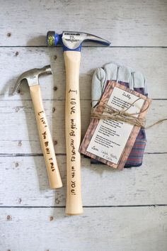 a hammer, glove and note sitting on top of a white wooden table next to a pair of gloves