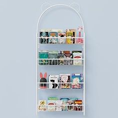 a white shelf with books and magazines on it against a blue wall in a room