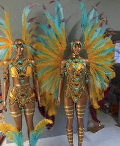 two mannequins dressed in gold and turquoise feathers