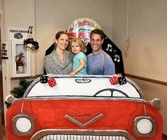 a man, woman and child are sitting on top of a car shaped cake that is decorated with music notes