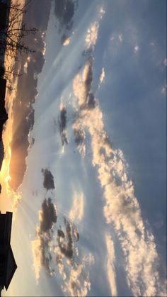 the sun is setting behind some clouds in the sky with buildings and trees on either side