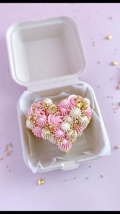 a heart shaped cake in a white box on a pink table with confetti