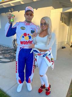 a man and woman dressed up in racing gear posing for a photo outside their house