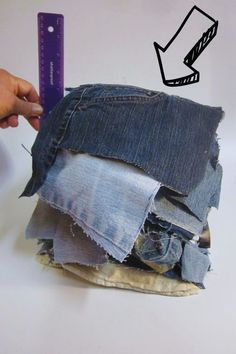 a person is holding a ruler over a pile of jeans that have been torn apart