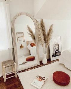 a bedroom with a mirror, stool and pictures on the wall next to a bed