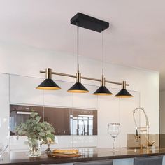 three lights hanging over a kitchen island in a room with white walls and flooring