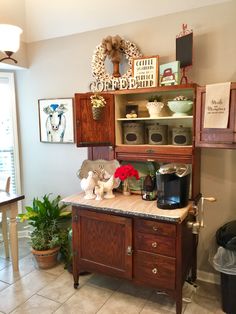 a kitchen area with a wooden cabinet, potted plants and pictures on the wall