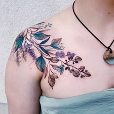 a woman's chest with blue flowers and leaves on her left side, tattoo style