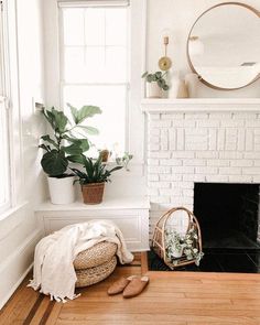 a living room with a fireplace, potted plant and wicker basket on the floor