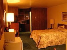 a hotel room with a bed, desk and microwave in it's corner area