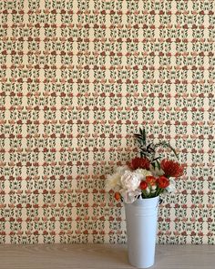 a vase filled with flowers sitting on top of a wooden table next to a wall