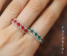 a woman's hand with a red, green and white ring on her finger