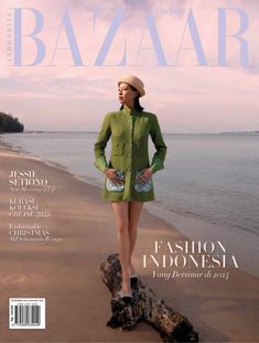 a woman standing on top of a tree stump next to the ocean in front of a magazine cover