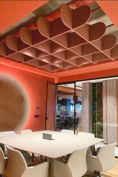 a conference room with orange walls and white chairs around a table in front of a large window