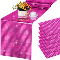 the table is covered with pink plastic squares and has flowers in a vase on it