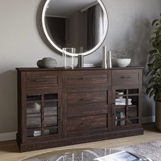 a large round mirror is on the wall above a dark wood sideboard with drawers