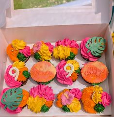 cupcakes in a box decorated with flowers and leaves for a tropical themed birthday party