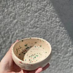 a hand holding a small white bowl with sprinkles on the outside and inside