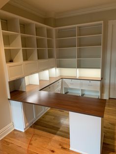 an empty room with white cabinets and wood flooring is pictured in this image, there are no people or objects on the shelves