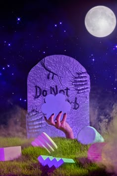 a person holding up a paper cut out in front of a grave with the words don't touch on it