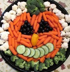 a plate with carrots, cauliflower and cucumbers in the shape of a face