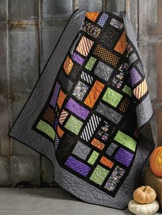 a quilted blanket sitting on top of a wooden table next to pumpkins and squash