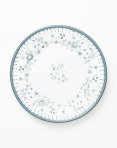 a white and blue plate with flowers on the rim, in front of a white background