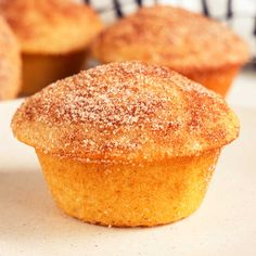 two sugary muffins on a plate with other muffins in the background