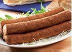 two sausages are on a plate with bread and lettuce in the background