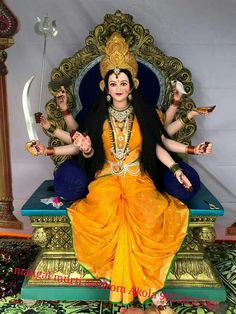 a statue of the hindu goddess sitting on a throne with two swords in her hands