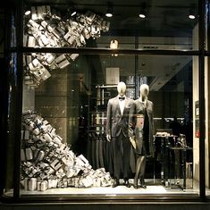 two mannequins dressed in black and white outfits stand behind a window display