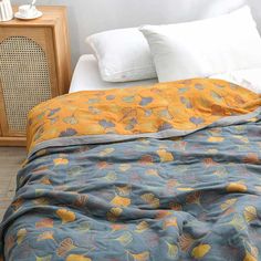 a bed with an orange and blue comforter on top of it next to a night stand