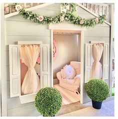 the doll house is decorated with pink and white decor, including two large potted plants