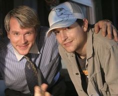 two men are posing for the camera with their arms around each other and one is wearing a hat