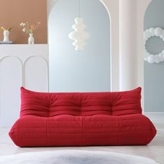 a red futon sofa sitting on top of a white rug in a living room