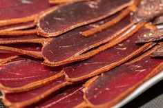 several slices of meat on a plate with other food items in the backround