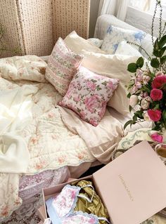 a bed with pink flowers on it next to a box of tissues and a bouquet of roses