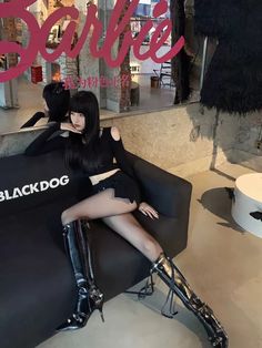 a woman sitting on top of a black dog chair in front of a store window