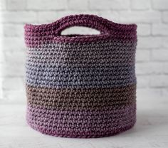 a crocheted basket is shown on a white surface with brick wall in the background