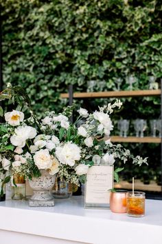 white flowers and greenery are on display at the reception table for guests to sit down