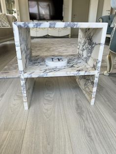 a white and grey marbled end table in a living room with hardwood floors, furniture and decor