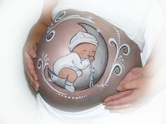 a pregnant woman is holding her belly painted with an image of a baby