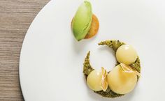 a white plate topped with two pieces of food on top of a wooden table next to a green leaf